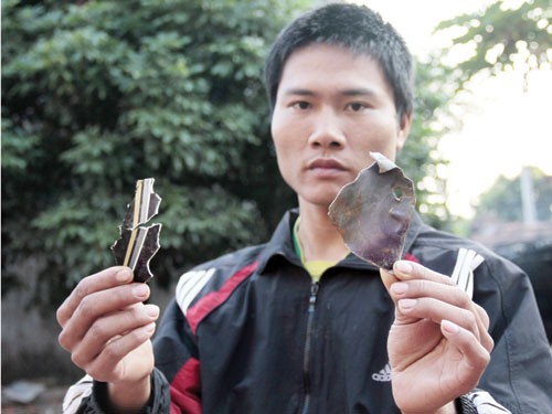 Nhân chứng Nguyễn Đức Thuận với các mảnh vụn, trong đó nhiều mảnh làm thủng tường gạch - Ảnh: Lê Quân